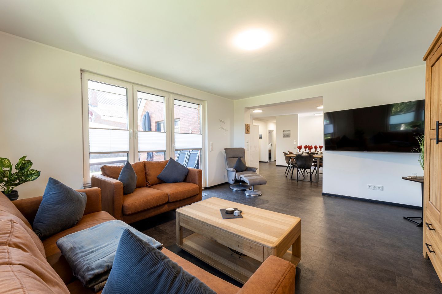 Un salon moderne comprenant un canapé, une table basse et un coin repas avec des chaises et un téléviseur.