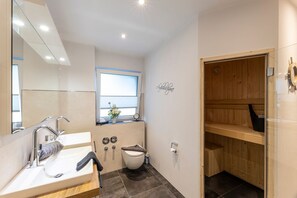 A modern bathroom with a large mirror, a sink, a toilet, and a shower area.
