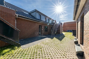 A courtyard with a brick building, a staircase, and a paved walkway.