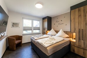 Quarto moderno com uma cama grande, mesas de cabeceira, uma cadeira e um guarda-roupa.
