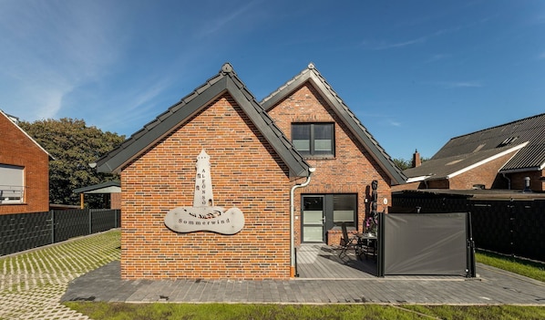 A brick building with a sign reading "Sommerwind" and a small attached structure with a door and a table.