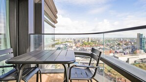 Een balkon met een tafel en stoelen, met uitzicht over de stad.
