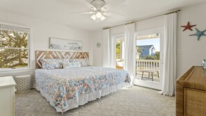 A bedroom with a bed, a ceiling fan, a window, and a view of the outside. - The Silly Geese: Pool Hot Tub Games, Walk to Beach (Corolla)