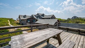 A wooden deck with benches overlooking a beachfront property with multiple houses. - Oceanfront, dog friendly, walkway to beach, cozy historic cottage- Island Dancer (Nags Head)