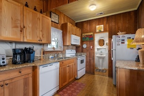 Compact kitchen with a stove, microwave, sink, dishwasher, and refrigerator.