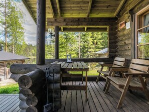 A wooden deck with a table and benches, a lantern, and a log stack.