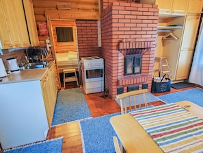 A compact kitchen with a brick stove, wooden cabinets, and a small dining area with a colorful rug.