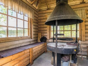 En rustik stuga med en stor kamin, träbänkar och stora fönster.