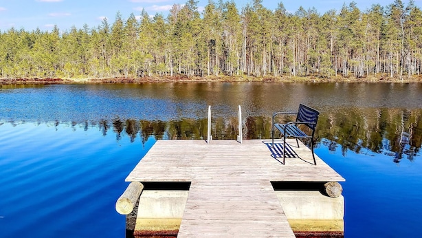 A wooden dock extending into a calm lake with a bench at the end. - Vacation home Ainola by Interhome (Joutsa)