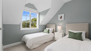 Ein Schlafzimmer mit zwei Betten, einem Fenster und einem Nachttisch.