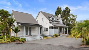 Ein zweistöckiges Haus mit grauem Dach, weißem Mauerwerk und einer überdachten Veranda.