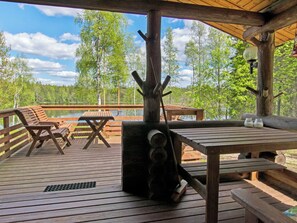 Una terraza de madera con mesas de picnic y bancos con vista a un lago.