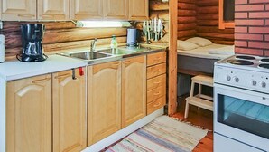 Una cocina compacta con armarios de madera, un lavamanos, una cafetera y una estufa.