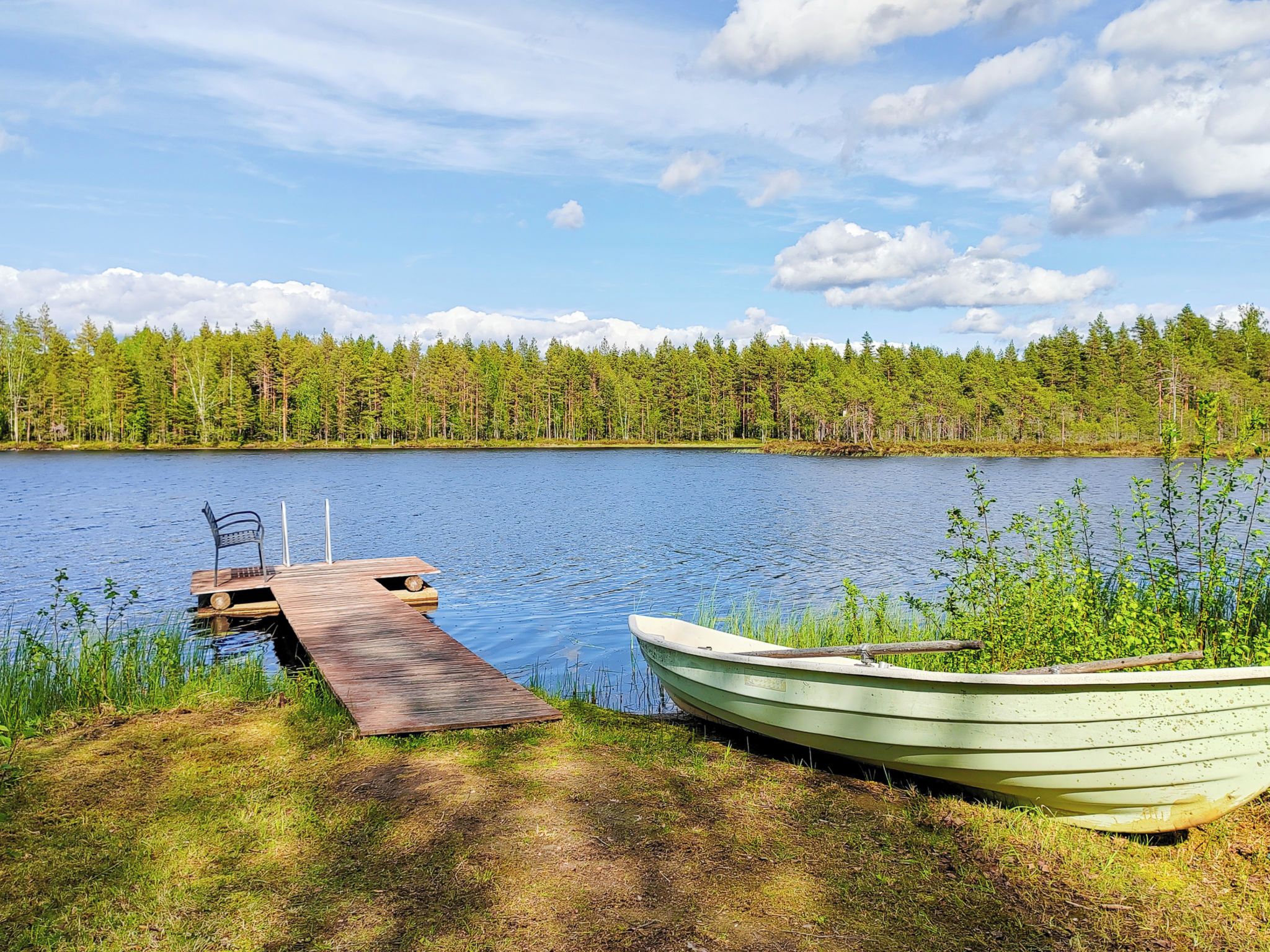 A calm lake with a dock and a boat.