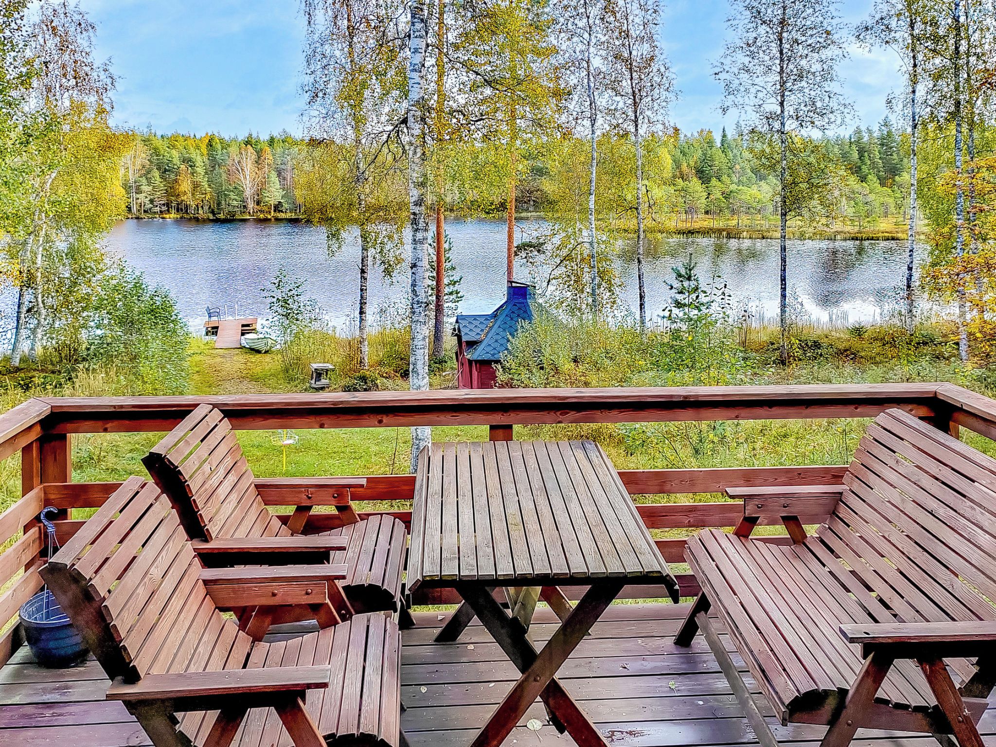 A wooden deck with benches overlooking a lake, surrounded by trees.