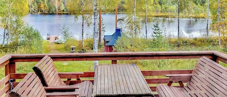 A wooden deck with benches overlooking a lake, surrounded by trees.