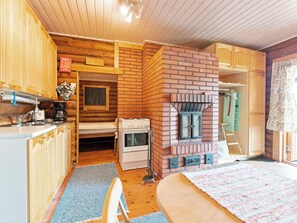 Kompakti keittiö, jossa on puukaapit, liesi ja tiilestä muurattu takka.
