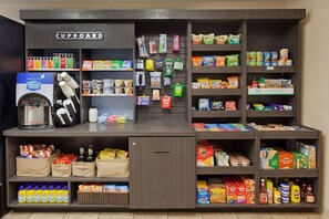 Un angolo cottura con macchina del caffè, diversi alimenti e un cartello con la scritta 'Cupboard'.