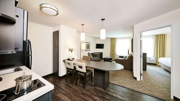A modern hotel room with a kitchenette, a dining area with a table and chairs, a sofa, a TV, and a bed. - Pet-friendly Lodging Near South Jersey Regional Airport! FREE Parking, Kitchen! (Mount Laurel Township)