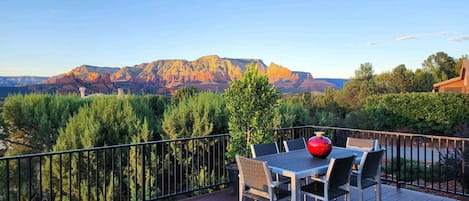 A deck with a table and chairs, overlooking a mountainous landscape.