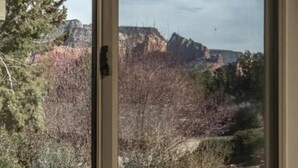 A view through a window of a mountainous landscape with trees and a clear sky.