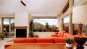 A modern living room with a large orange sofa, a wooden coffee table, and a fireplace.