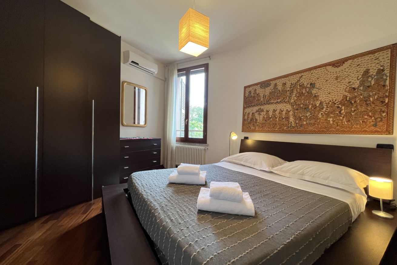 Un dormitorio con una cama grande, un armario oscuro y una obra de arte colgada en la pared.