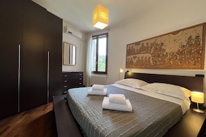 Ein Schlafzimmer mit einem großen Bett, einem dunklen Wandschrank und einem an der Wand hängenden Kunstwerk.