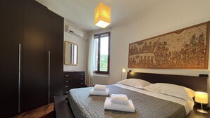 Un dormitori amb un llit gran, un armari fosc i una obra d'art penjada a la paret.