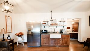 A modern kitchen with a stainless steel refrigerator, wooden cabinets, and a built-in island with a sink.