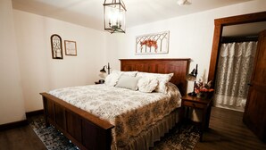 A bedroom with a wooden bed, a nightstand, a wall clock, and a decorative wall piece.