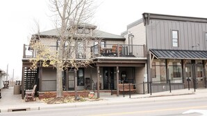A two-story building with a balcony, a covered entrance, and a tree in front.
