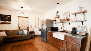 A kitchen with wooden cabinets, a stainless steel refrigerator, a sink, and a countertop with shelves.