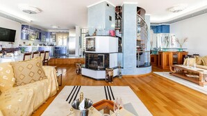 Una sala de estar moderna con chimenea, comedor y cocina con televisor.