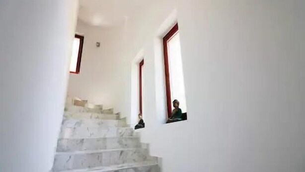 A staircase with white walls and red window frames.