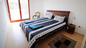 A bedroom with a wooden bed, a chair, a rug, and a window.