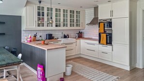 Eine moderne Küche mit weißen Schränken, einer zentralen Kochinsel und einem eingebauten Backofen.