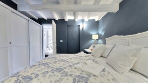A bedroom with a bed, white walls, a dark door, and a nightstand with a lamp. - Santo Spirito Romantic by Mmega (Firenze)