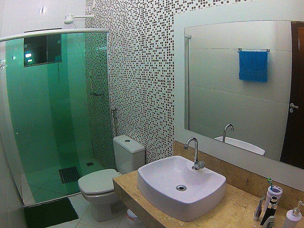 Un baño con cabina de ducha de vidrio, un lavabo blanco y un espejo encima.