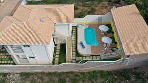 Propiedad residencial con piscina, mobiliario exterior y una escalera que conduce a un balcón.