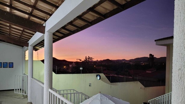 Un espacio al aire libre techado con vistas a la puesta de sol sobre un paisaje montañoso.