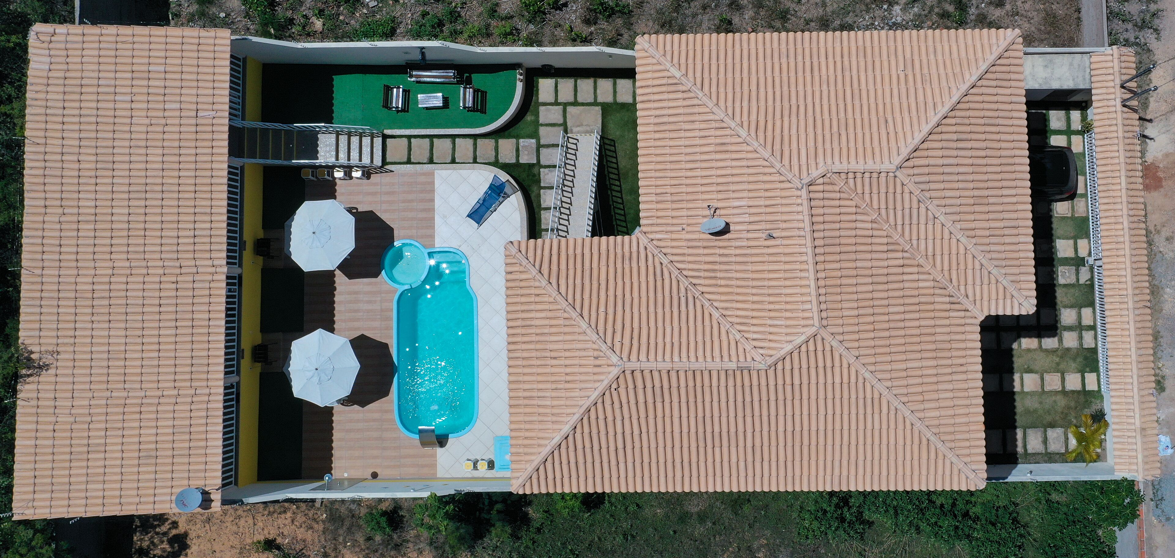 Vista aérea de una propiedad con piscina, mobiliario exterior y un patio cubierto.