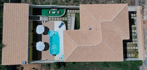 Eine Vogelperspektive zeigt ein Anwesen mit Schwimmbad, Außenbereich und einer überdachten Terrasse.