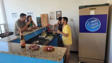 A kitchen area with a bar counter, a refrigerator, and a wall with decorative signs.