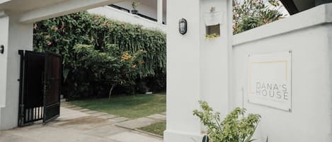 A white building with a sign reading "Dana's House" and a black gate.