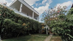 A modern building with a flat roof, surrounded by lush greenery and a well-maintained garden. - Dana's House (Tabanan)