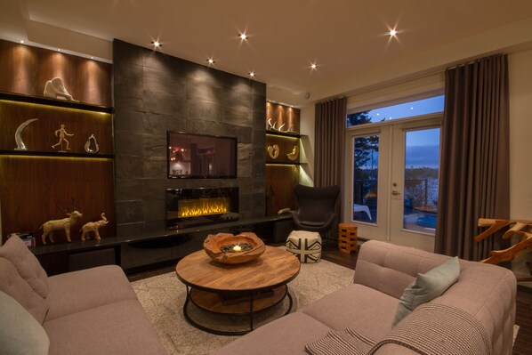 A modern living room with a fireplace, comfortable seating, and decorative shelves. - Seacliff- Luxury Halifax Waterfront Paradise -Pool, Hot Tub, Wharf & Boathouse (Halifax)