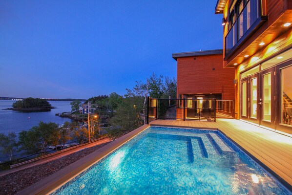 A swimming pool adjacent to a building with a view of a body of water and a small island. - Seacliff- Luxury Halifax Waterfront Paradise -Pool, Hot Tub, Wharf & Boathouse (Halifax)