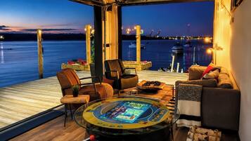 Un espace terrasse accueillant avec vue sur l’eau, une table ronde pour jouer et des sièges confortables.