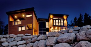 A modern two-story house with large windows, a stone wall in the foreground, and a clear sky. - Seacliff- Luxury Halifax Waterfront Paradise -Pool, Hot Tub, Wharf & Boathouse (Halifax)